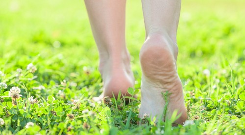 женщина идёт без обуви по траве